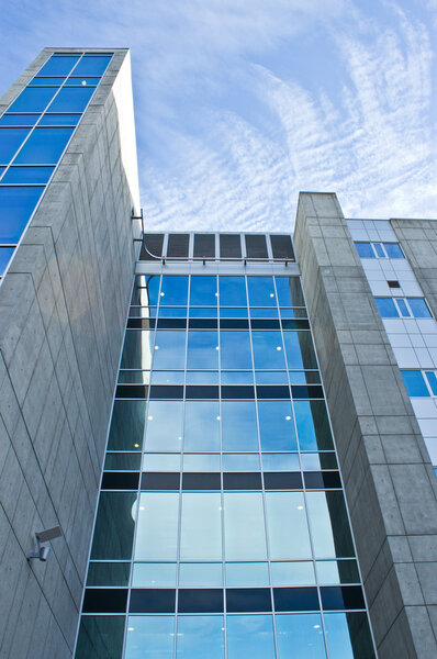 Angle shot of glass and concrete highrise with cloudscape