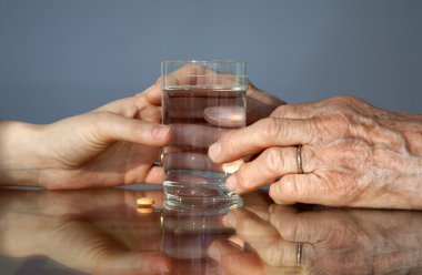 Hand of grandmother and women with a pill clipart