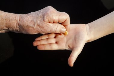 Hand of grandmother and grandchild with a pill clipart