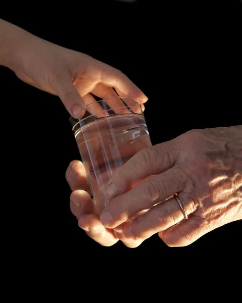 Руки бабушки и внука со стаканом воды — стоковое фото