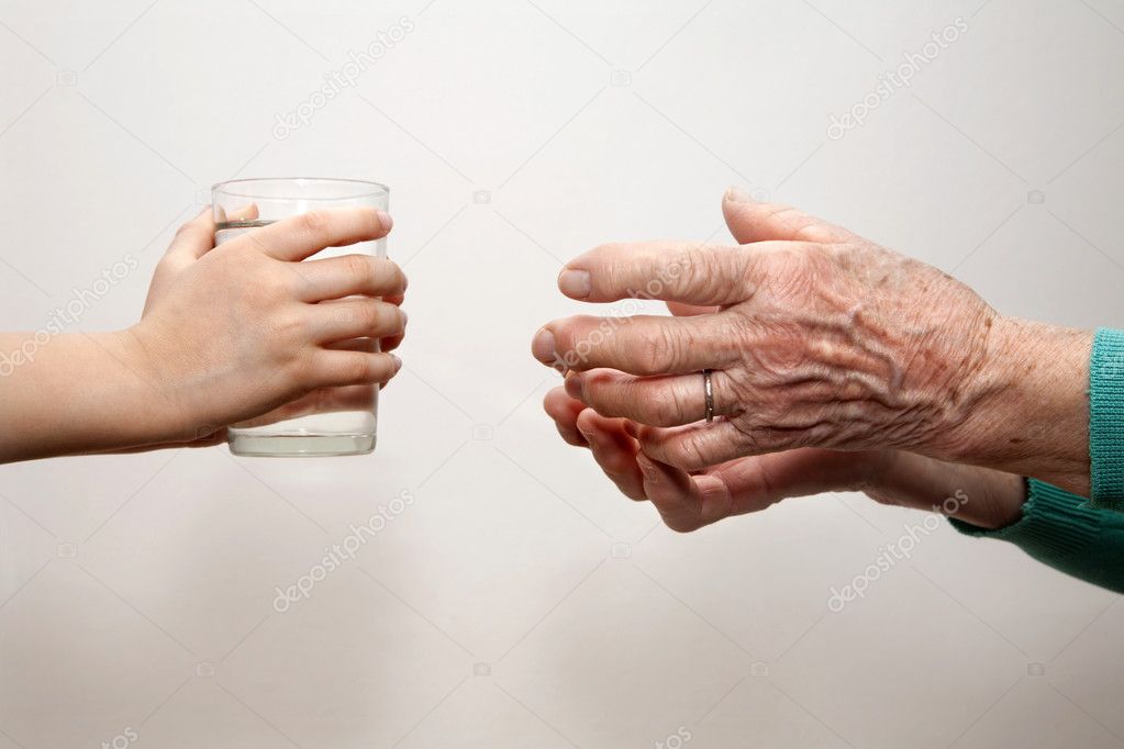 Hands of grandmother and grandchild with the glass of water