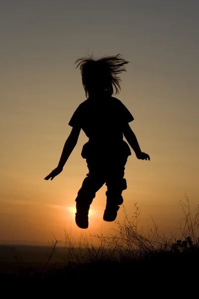 Άλμα του κοριτσάκι στο ηλιοβασίλεμα - σιλουέτα — Φωτογραφία Αρχείου
