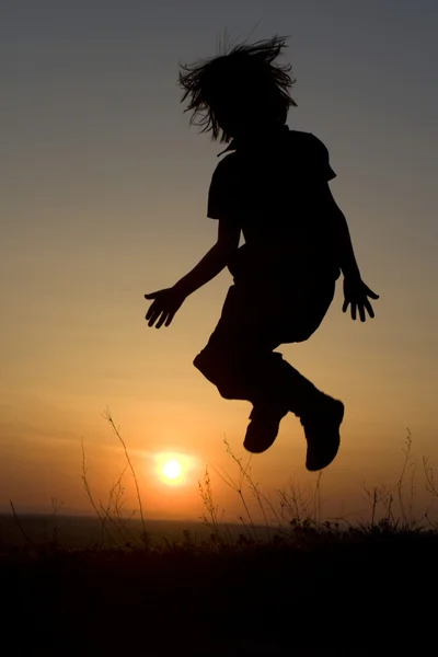 Springen van meisje in zonsondergang - silhouet — Stockfoto