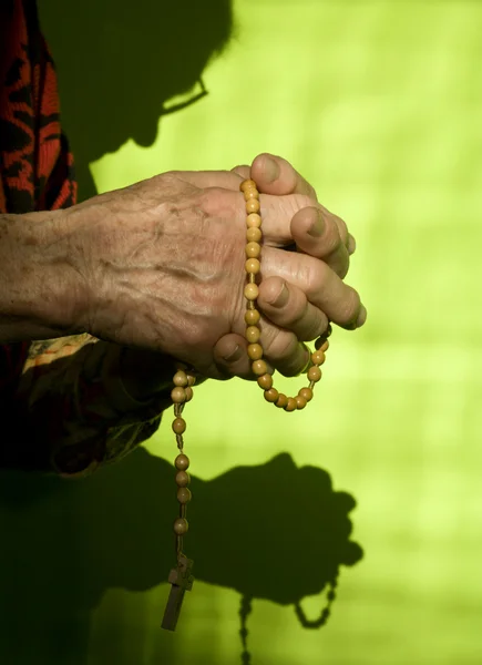 Manos de anciana rezando rosario — Foto de Stock