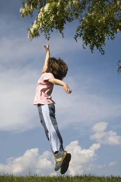 Skok z holčička a strom na jaře — Stock fotografie