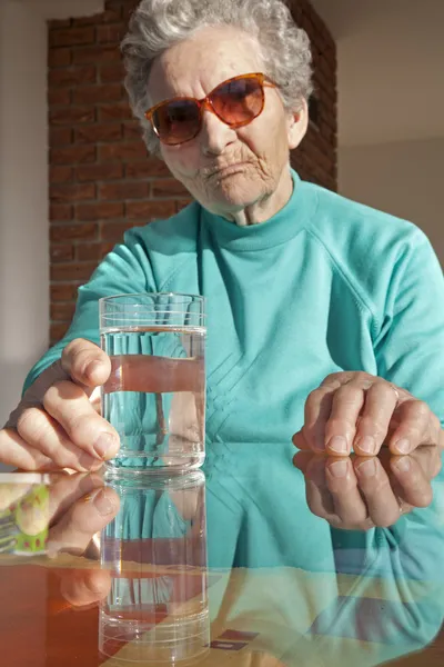 Glas water en oude vrouw — Stockfoto