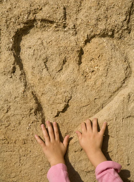 Cuore nella sabbia e nella mano del bambino — Foto Stock