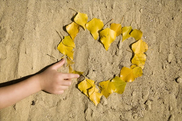 Serce w piasku i dłoni dziecka — Zdjęcie stockowe