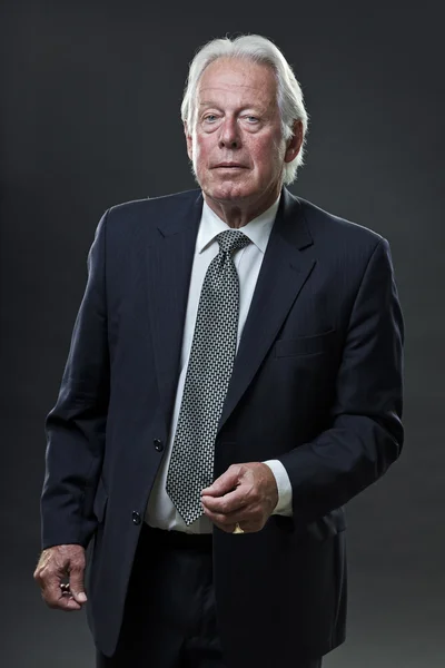 Hombre de negocios senior con traje azul oscuro y corbata aislada sobre fondo oscuro . —  Fotos de Stock