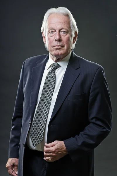 Homem de negócios sênior com terno azul escuro e gravata isolada no fundo escuro . — Fotografia de Stock