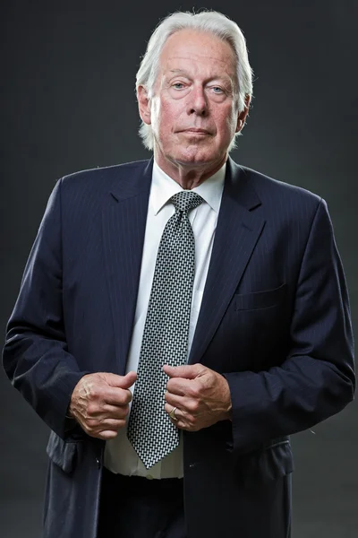 Hombre de negocios senior con traje azul y corbata aislada sobre fondo oscuro . —  Fotos de Stock