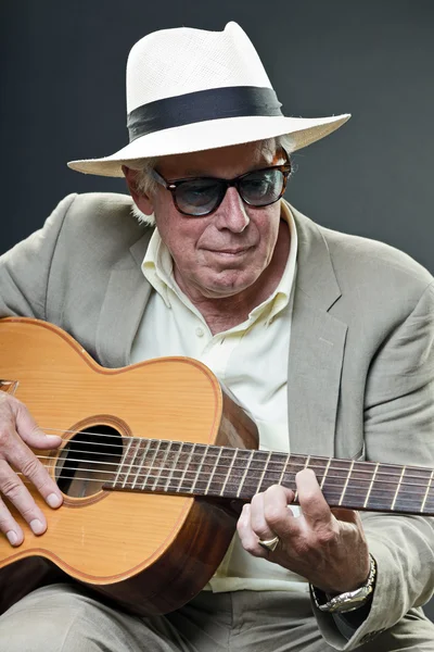 Senior jazzový hudebník s akustická kytara, nosit pokrývku hlavy a sluneční brýle. — Stock fotografie