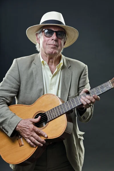 Senior jazzový hudebník s akustická kytara, nosit pokrývku hlavy a sluneční brýle. — Stock fotografie