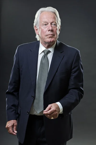 Uomo d'affari anziano in giacca e cravatta isolato su sfondo grigio . — Foto Stock