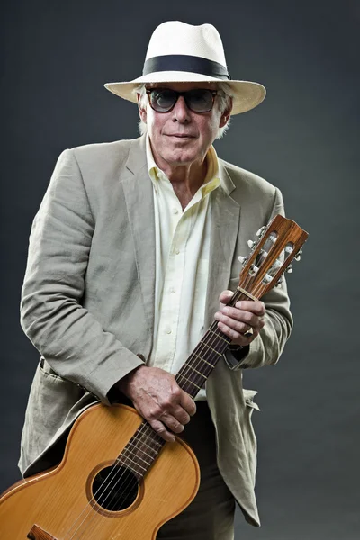 Senior férfi öltöny kalapot és napszemüveget visel, akusztikus gitár. — Stock Fotó