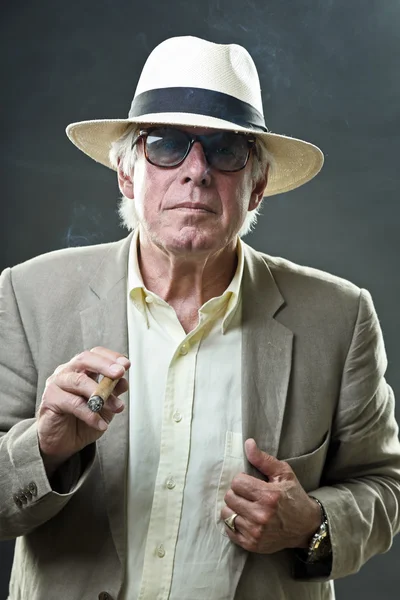 Äldre man med hatt och solglasögon röka cigarr. — Stockfoto