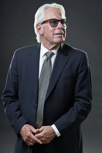 Homme d'affaires senior avec des lunettes de soleil isolées sur fond gris . — Photo