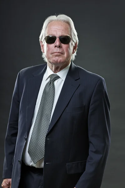 Senior-Geschäftsmann mit Sonnenbrille auf grauem Hintergrund. — Stockfoto