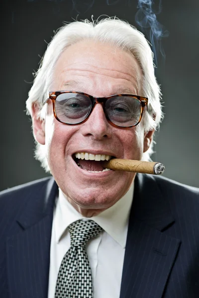 Senior obchodní muž kouření doutník nošení vinobraní sluneční brýle a modrý oblek s kravatou. — Stock fotografie