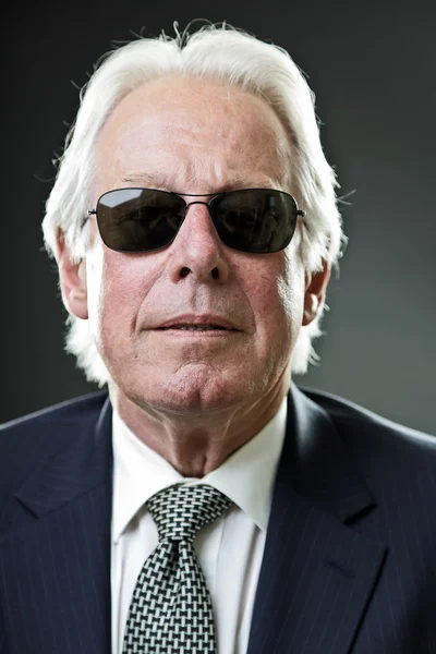 Senior fresco hombre de negocios con traje azul oscuro y corbata con gafas de sol negras . — Foto de Stock