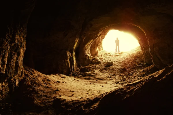Uomo in piedi davanti all'ingresso di una grotta — Foto Stock