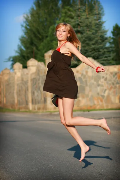 Ung flicka hoppar på vägen — Stockfoto