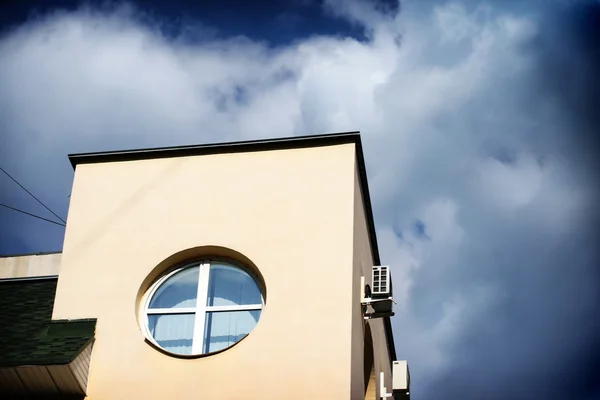 Casa com janela redonda no fundo céu azul — Fotografia de Stock