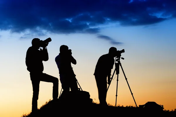 Três silhuetas de homem fotografando o céu — Fotografia de Stock