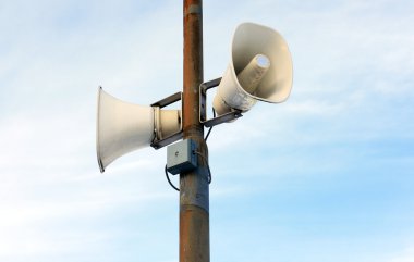 Two white outdoor loudspeakers against the sky clipart