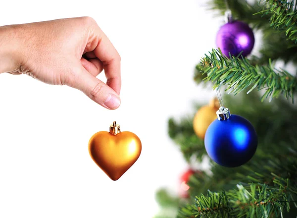 Hand decorating christmas tree with golden heart — Stock Photo, Image