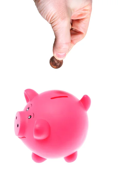 Hand inserting coin into piggy bank — Stock Photo, Image