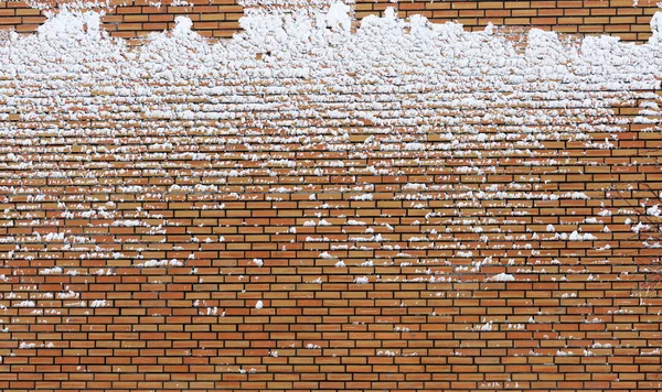 stock image Frozen orange brick wall covered with snow