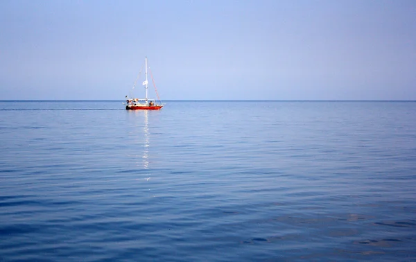 Et ensomt sejl i havet - Stock-foto