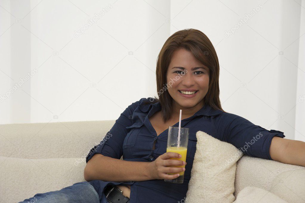 Beautiful women relaxing with orange-juice on the sofa