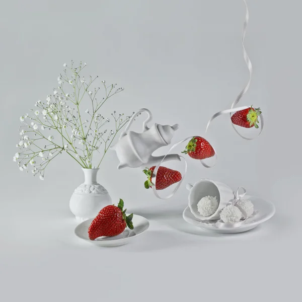 Flying strawberries with white ribbon and decorative dishes. — Stock Photo, Image