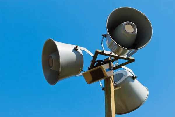 Three loudspeakers on a column against the blue sky Stock Picture