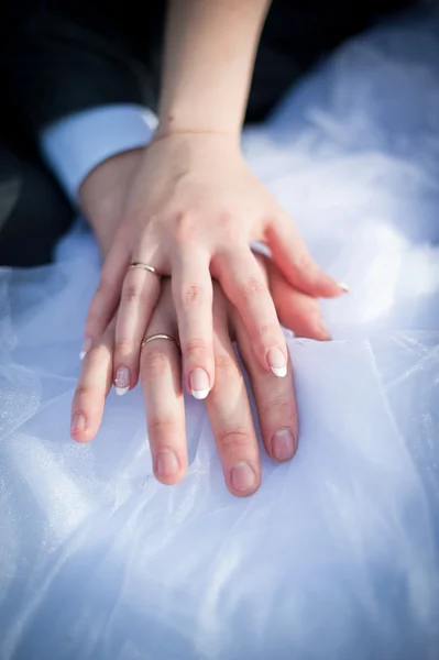 Руки молодоженов на белом платье — стоковое фото