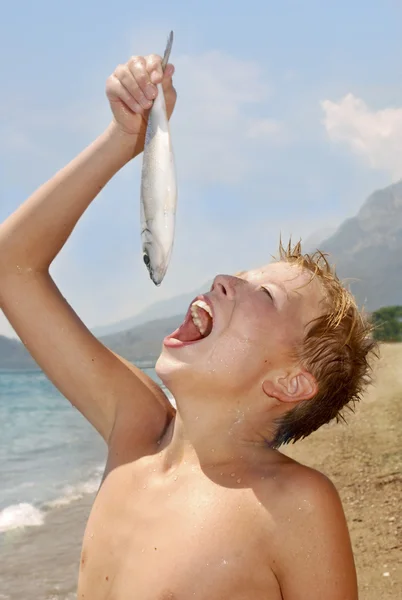 O rapaz finge que come peixe. — Fotografia de Stock