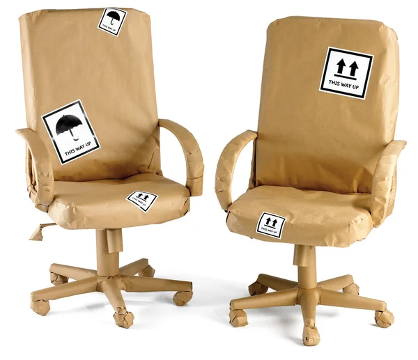 Krzesła biurowe zawinięte w papier brązowy gotowy do przenieść na białym tle o — Zdjęcie stockowe