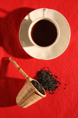 A wicker scoop with herb tea leaves and a cup of tea clipart