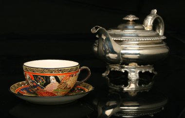 Çin fincan içine çay dökülen gümüş çaydanlık