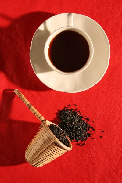 Плетеная сенсация с травяными чайными листьями и чашкой чая — стоковое фото