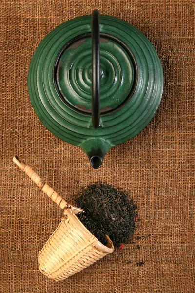 Théière chinoise et une cuillère en osier avec des feuilles de thé aux herbes — Photo