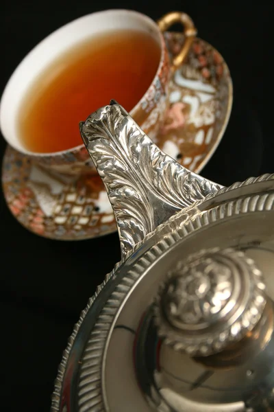 Серебряный чайник наливает чай в китайский кубок — стоковое фото