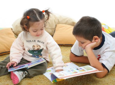 Brother and sister reading books on the floor clipart