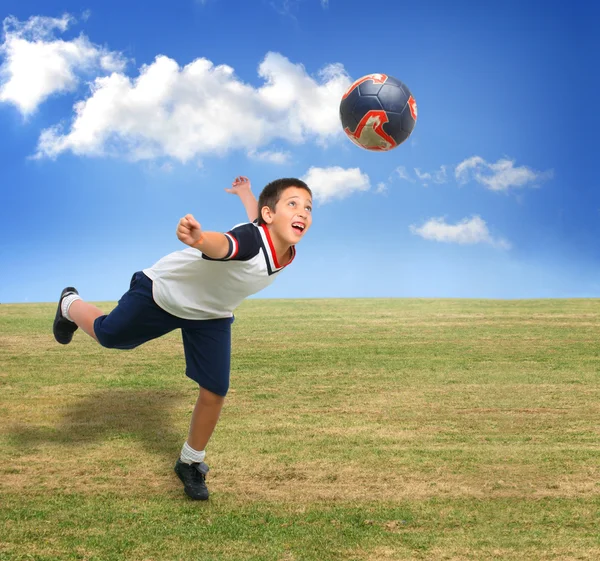 Un gamin joue au foot dehors. — Photo