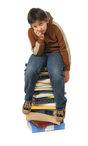 Estudante sentado em uma pilha de livros — Fotografia de Stock