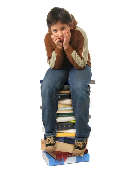 Estudante sentado em uma pilha de livros — Fotografia de Stock