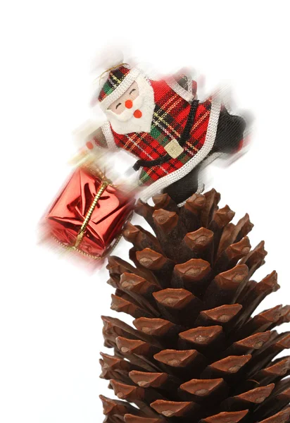 Santa com caixa de presente sobre um cone de pinho — Fotografia de Stock