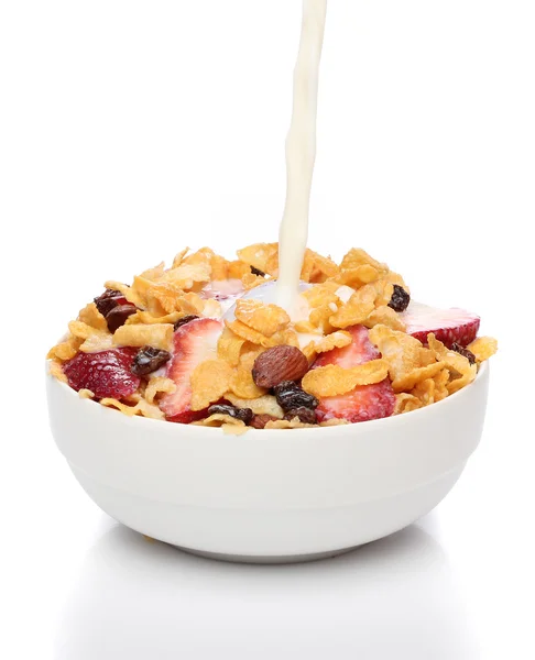 Pouring milk into a bowl of cornflakes and fruits — Stock Photo, Image